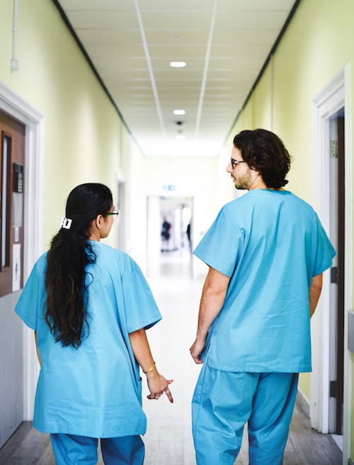 Back view of two doctors in blue scrubs in a hospital