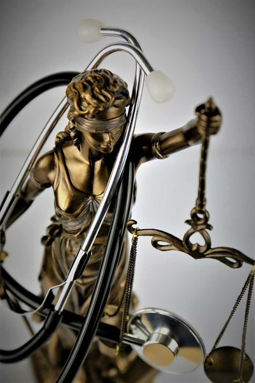 A gold scale of justice statue holding a stethoscope