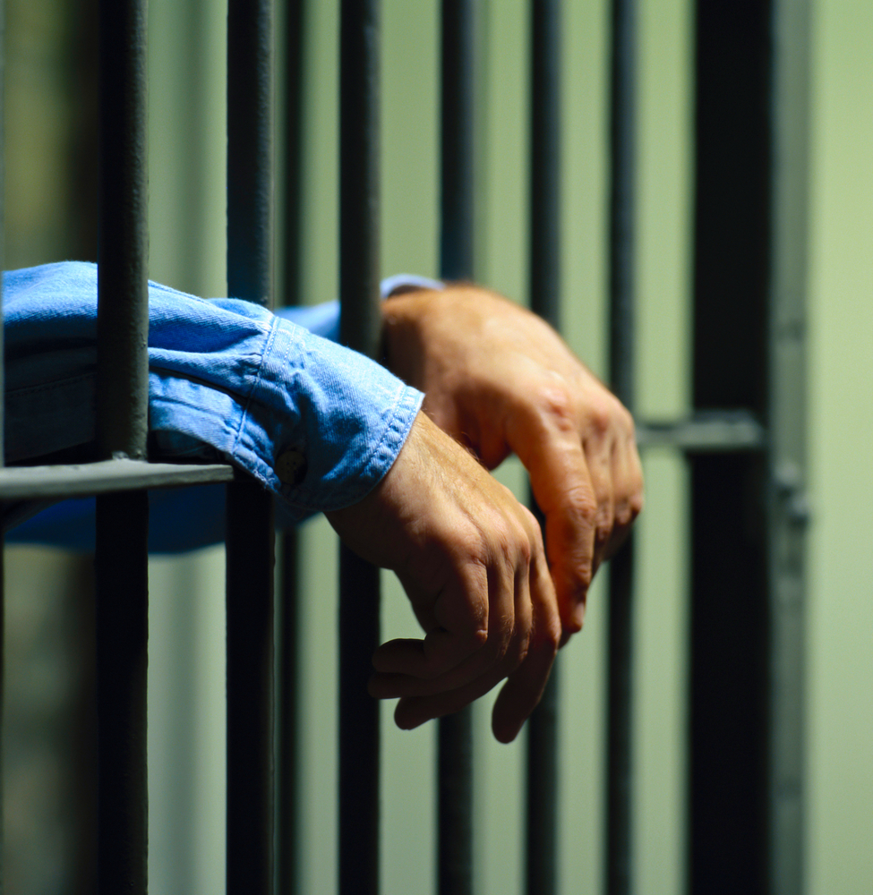Hands of an inmate through a jail cells gates