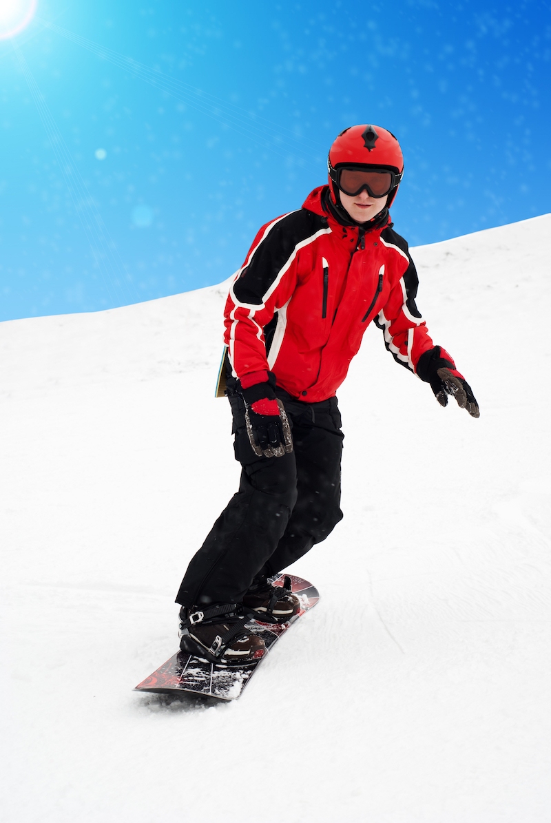 A person in a red and black outfit snowboarding