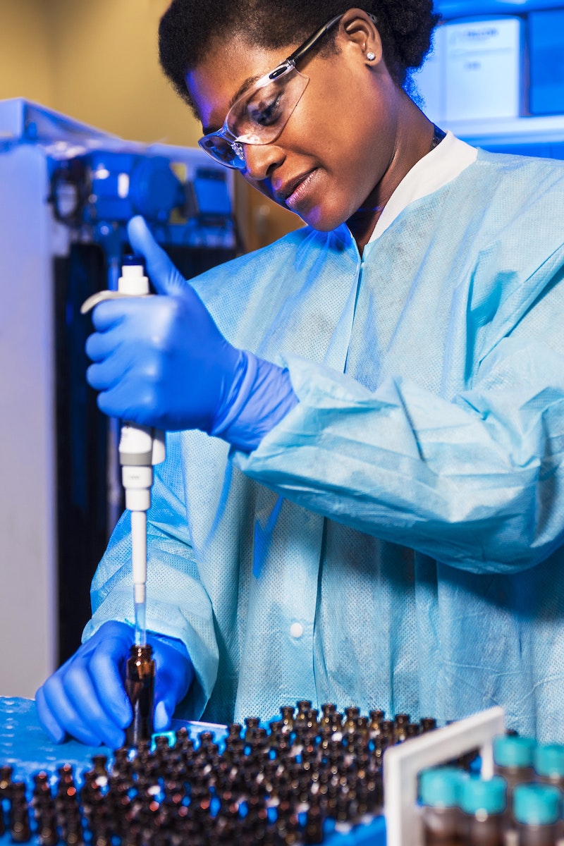 Doctor in blue scrubs filling bottles with medecine