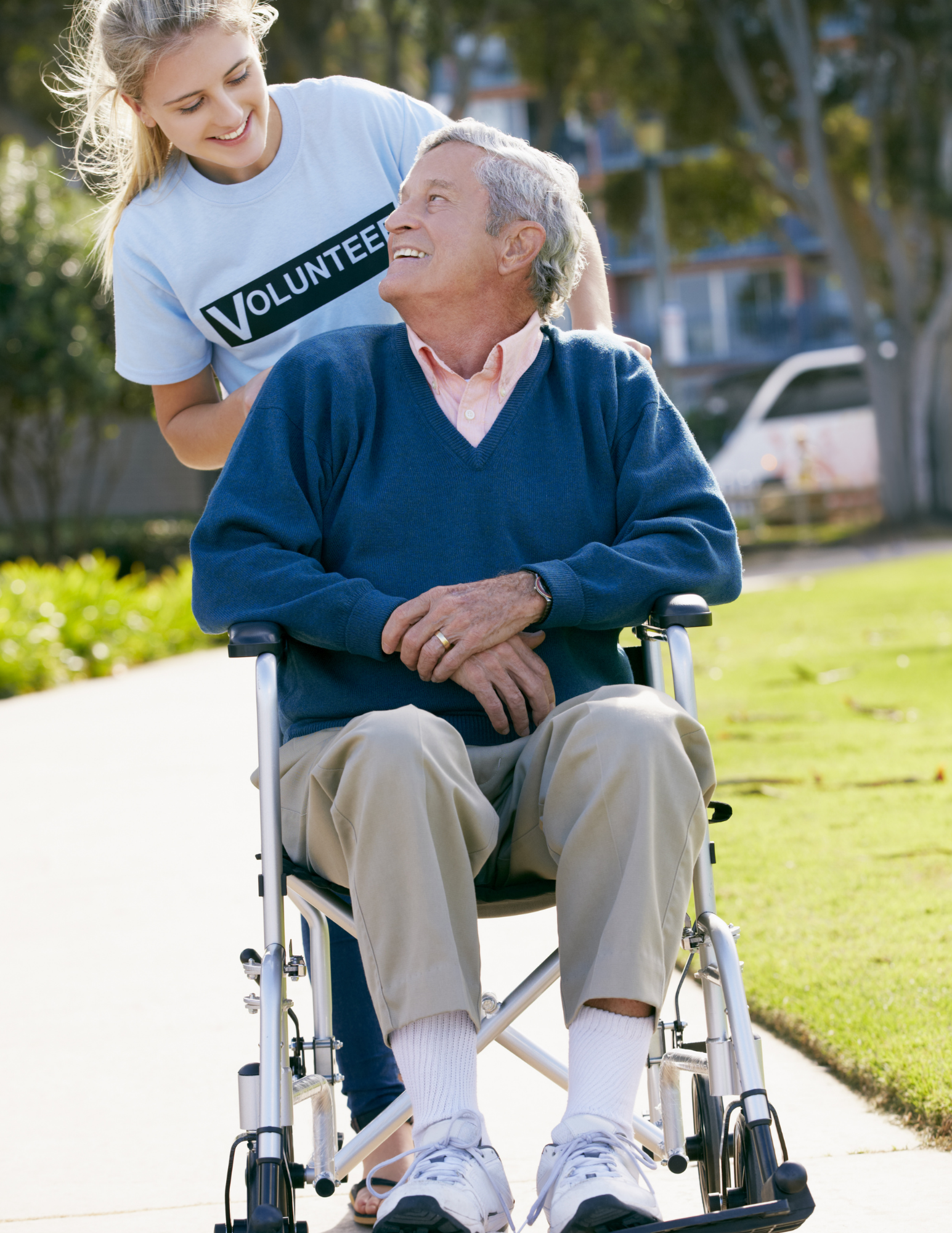 A volunteer pushing an elderly man in a wheelchair