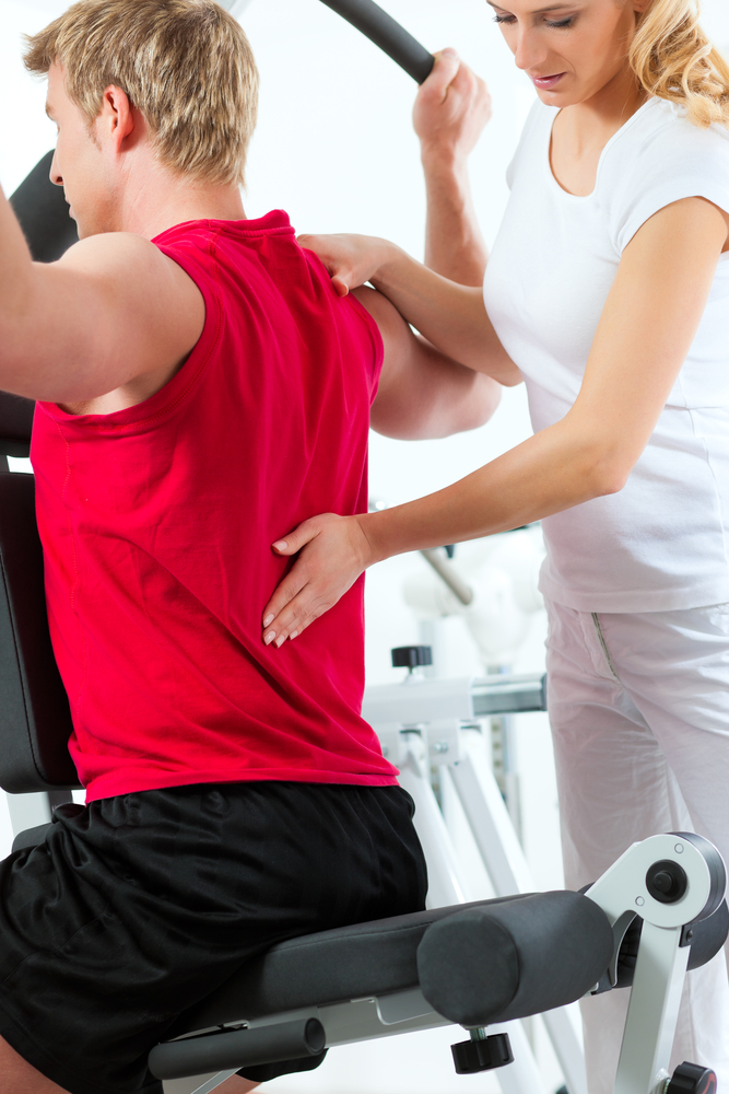 A male in a red shirt working out and a woman assisting him