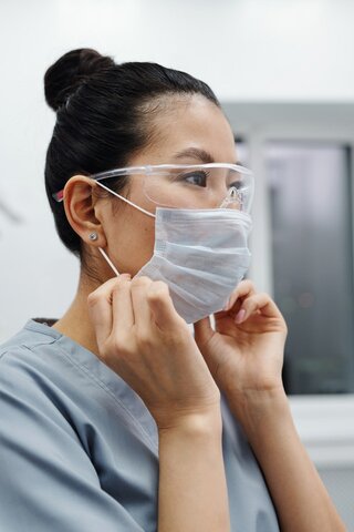 A female doctor in gray scrubs and a gray medical mask
