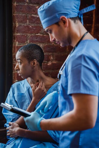 A doctor in blue scrubs looking at a clipboard